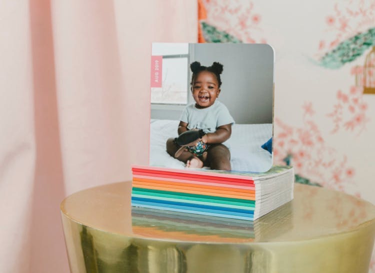 Stack of monthly photo books with baby on the cover on gold side table