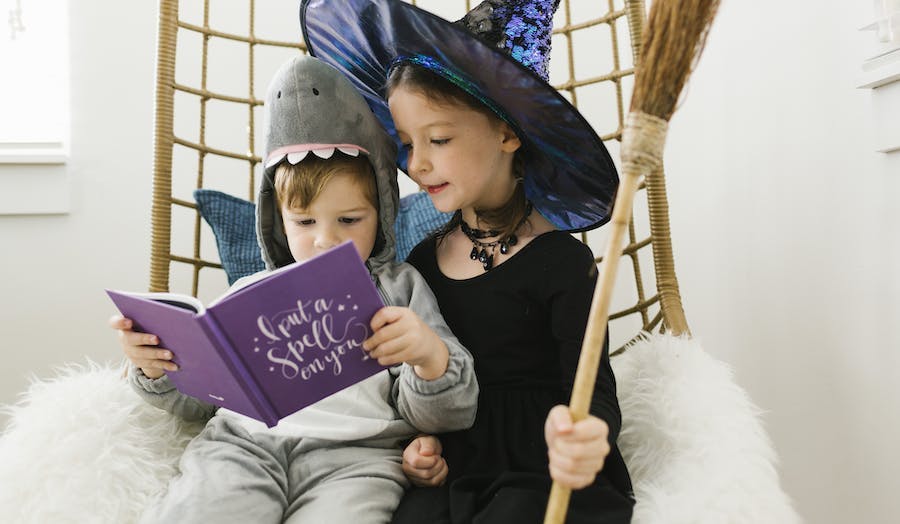 Brother and sister are dressed up for Halloween and looking through a Halloween Chatbook