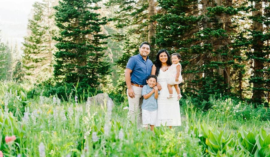 Family poses for family photos in a field of flowers and trees
