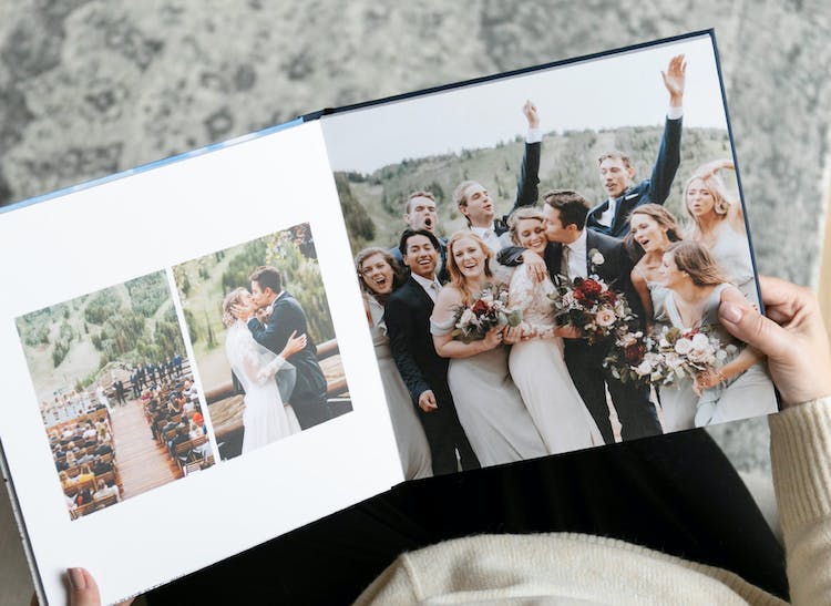 lay flat wedding album open showing bridal party with groom kissing bride